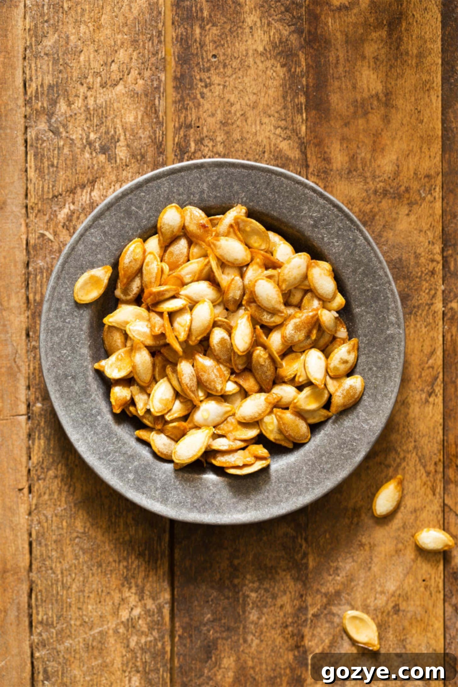 Roasted butternut squash seeds in a decorative silver bowl, showcasing their golden brown crispness, ready to be enjoyed.