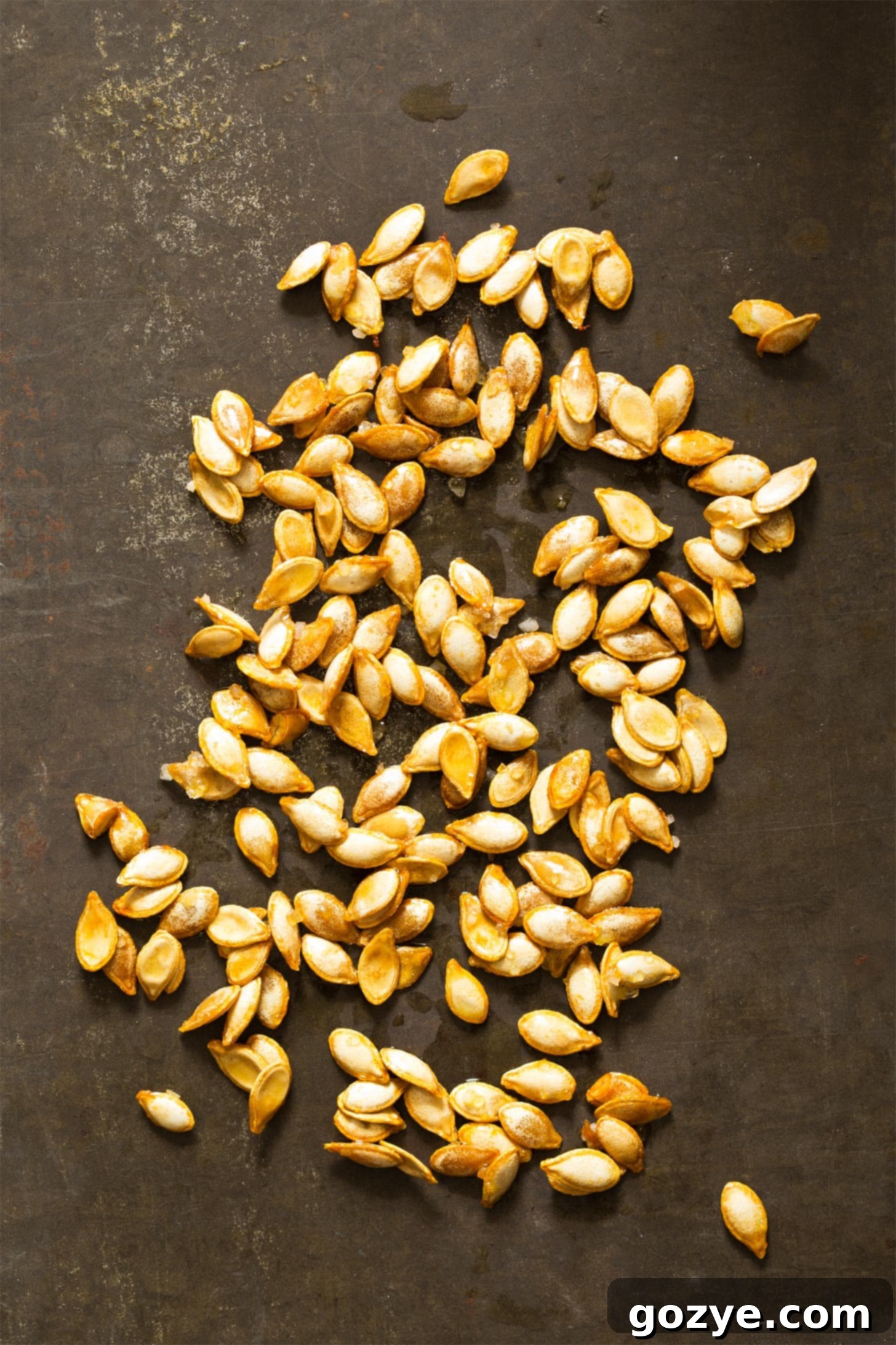 Butternut squash seeds spread evenly on a baking tray, ready for roasting, demonstrating the simple preparation.