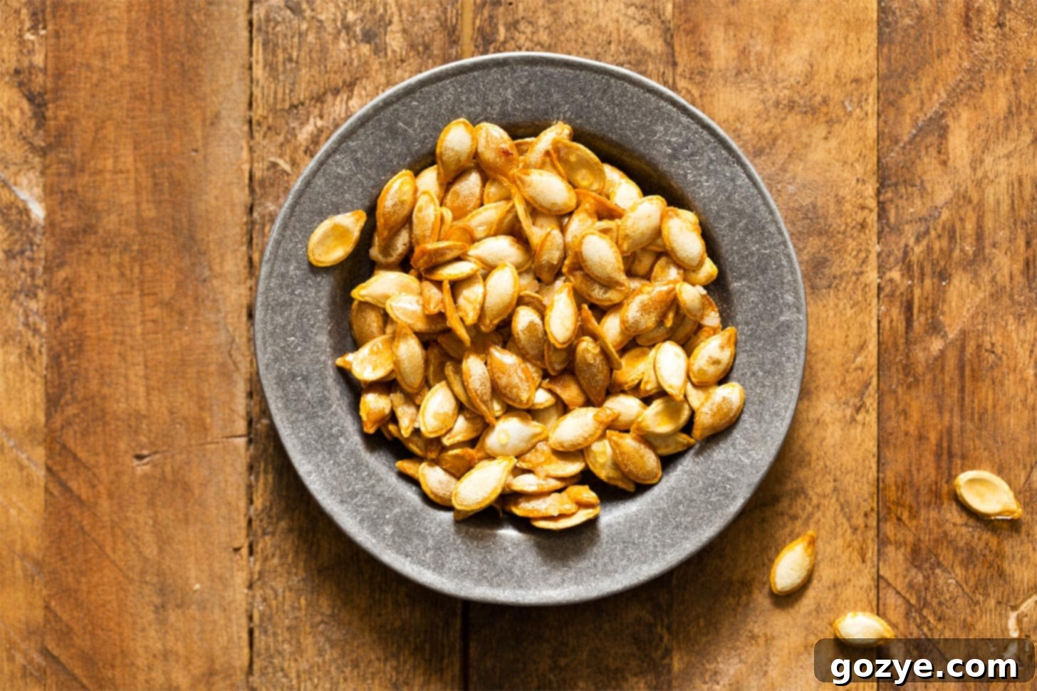 Close-up of roasted butternut squash seeds in a silver bowl, highlighting their crispy texture and delicious appeal.