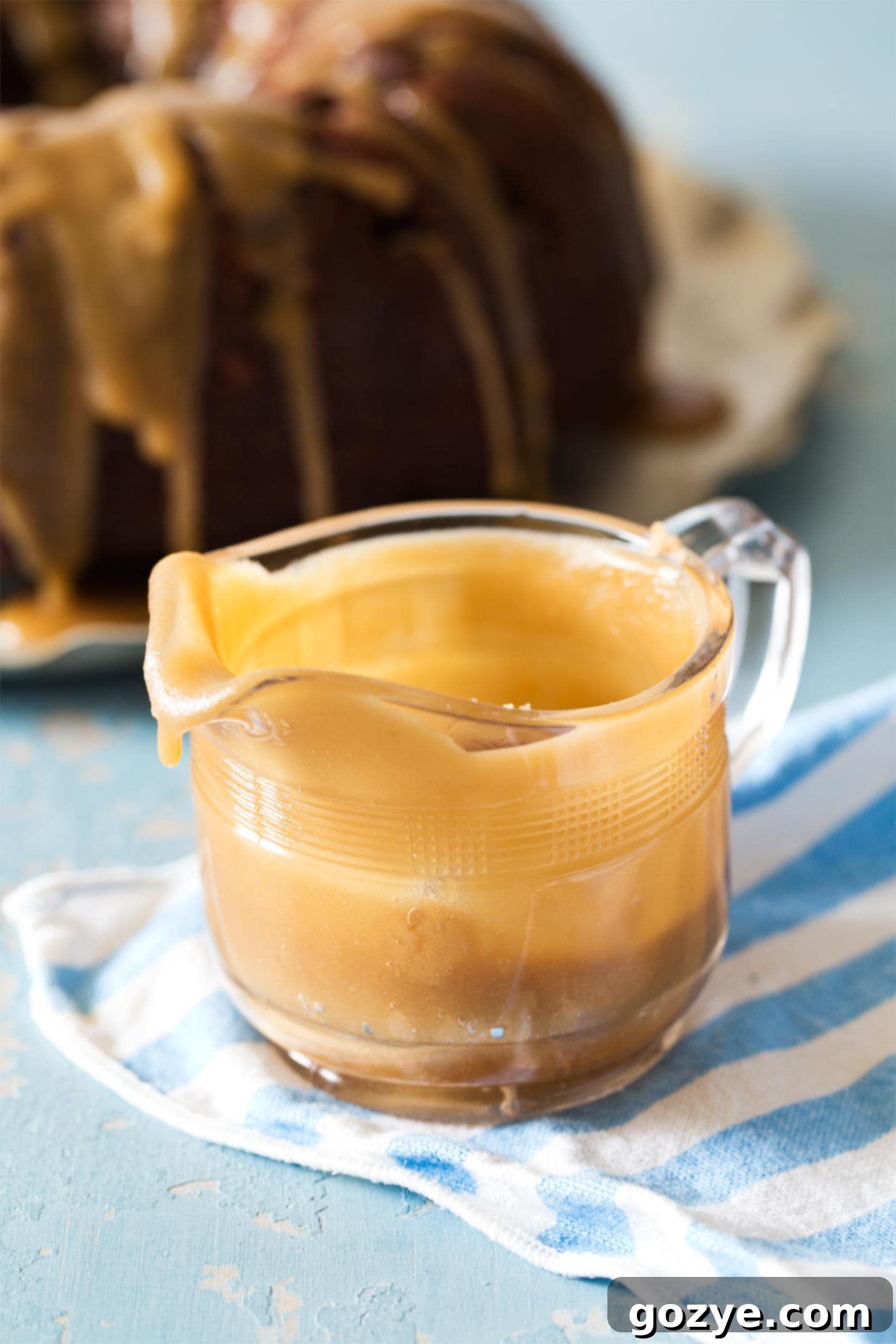 Glass pitcher filled with golden caramel glaze, ready for drizzling over desserts