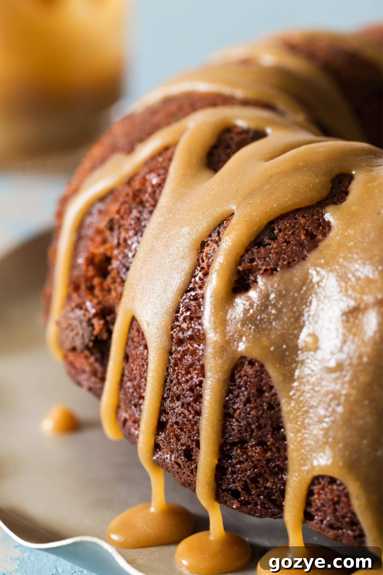 Close up shot of creamy caramel icing drizzled beautifully on a bundt cake, showing rich texture