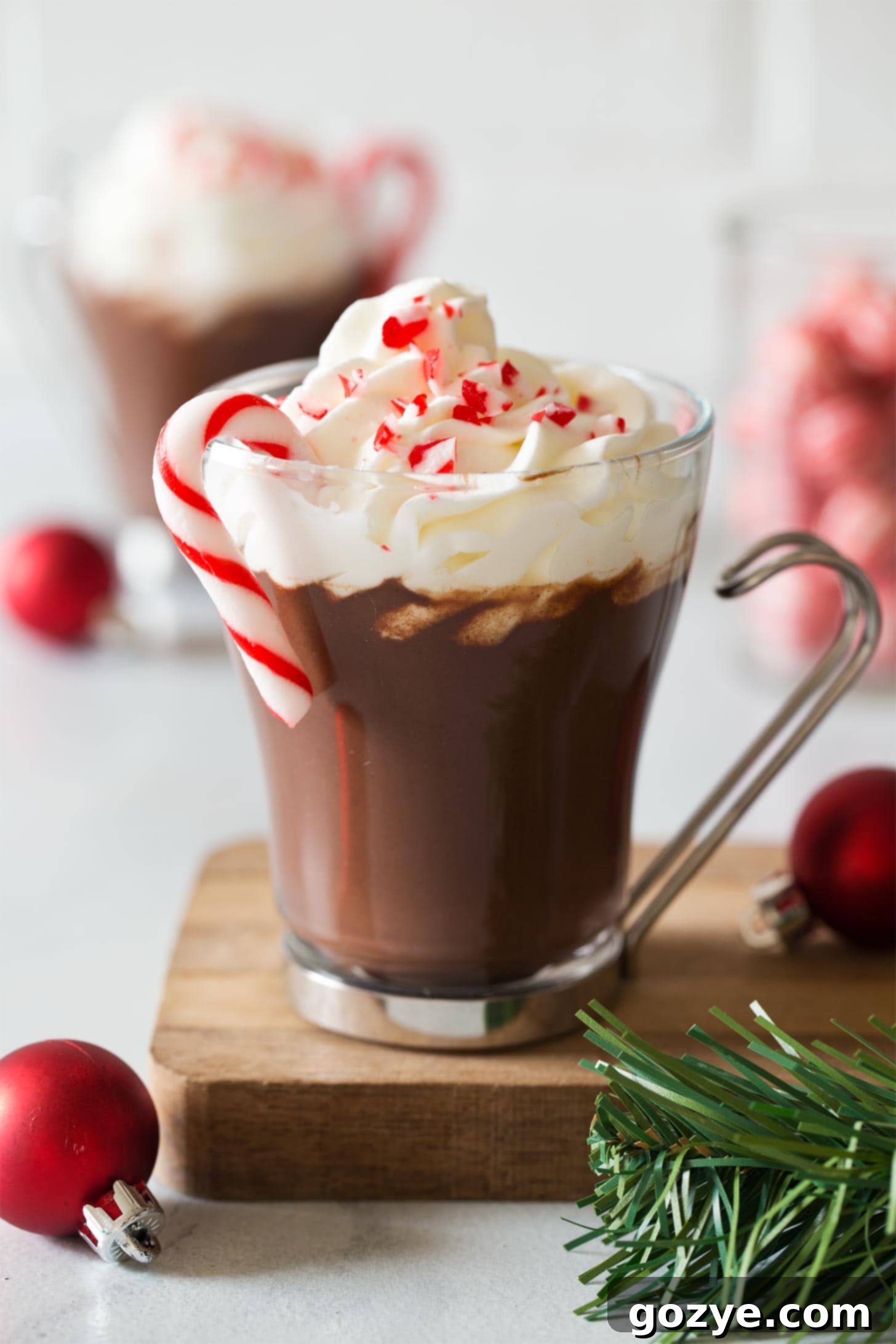 Delicious Peppermint Hot Chocolate in a glass, adorned with whipped cream and a candy cane
