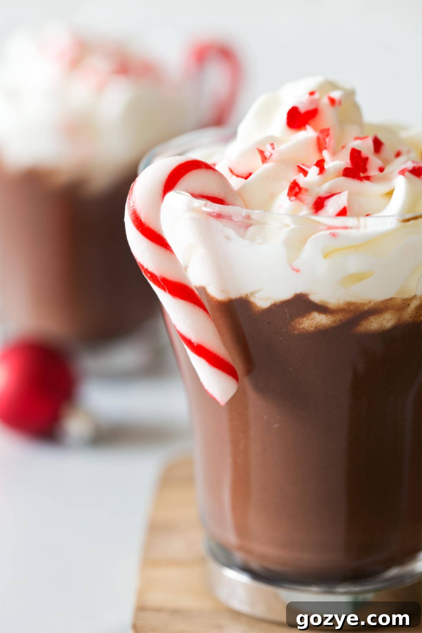 A mug of Peppermint hot cocoa, complete with a candy cane for stirring