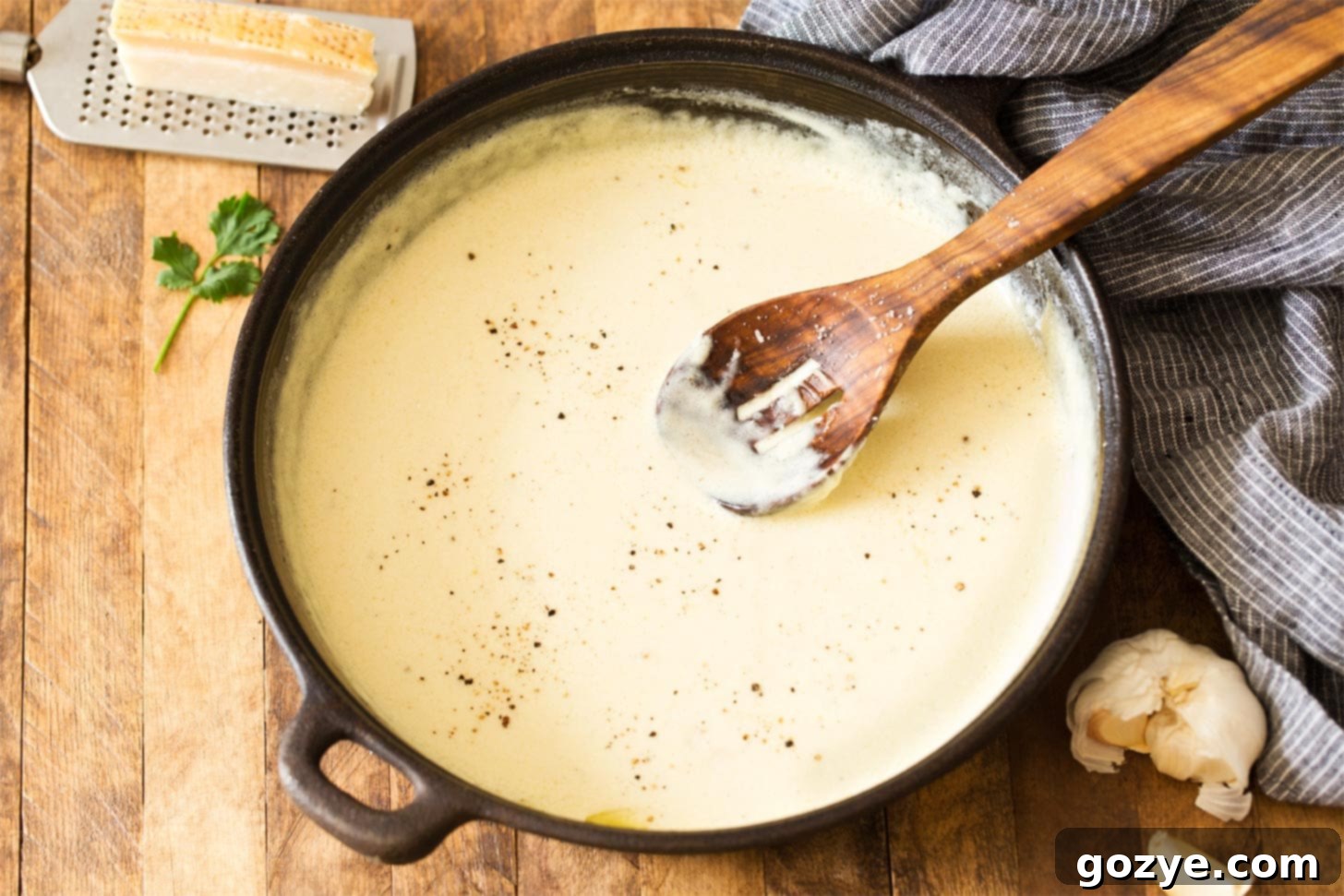 Small batch alfredo sauce simmering gently in a skillet, showing the creamy texture and rich color.