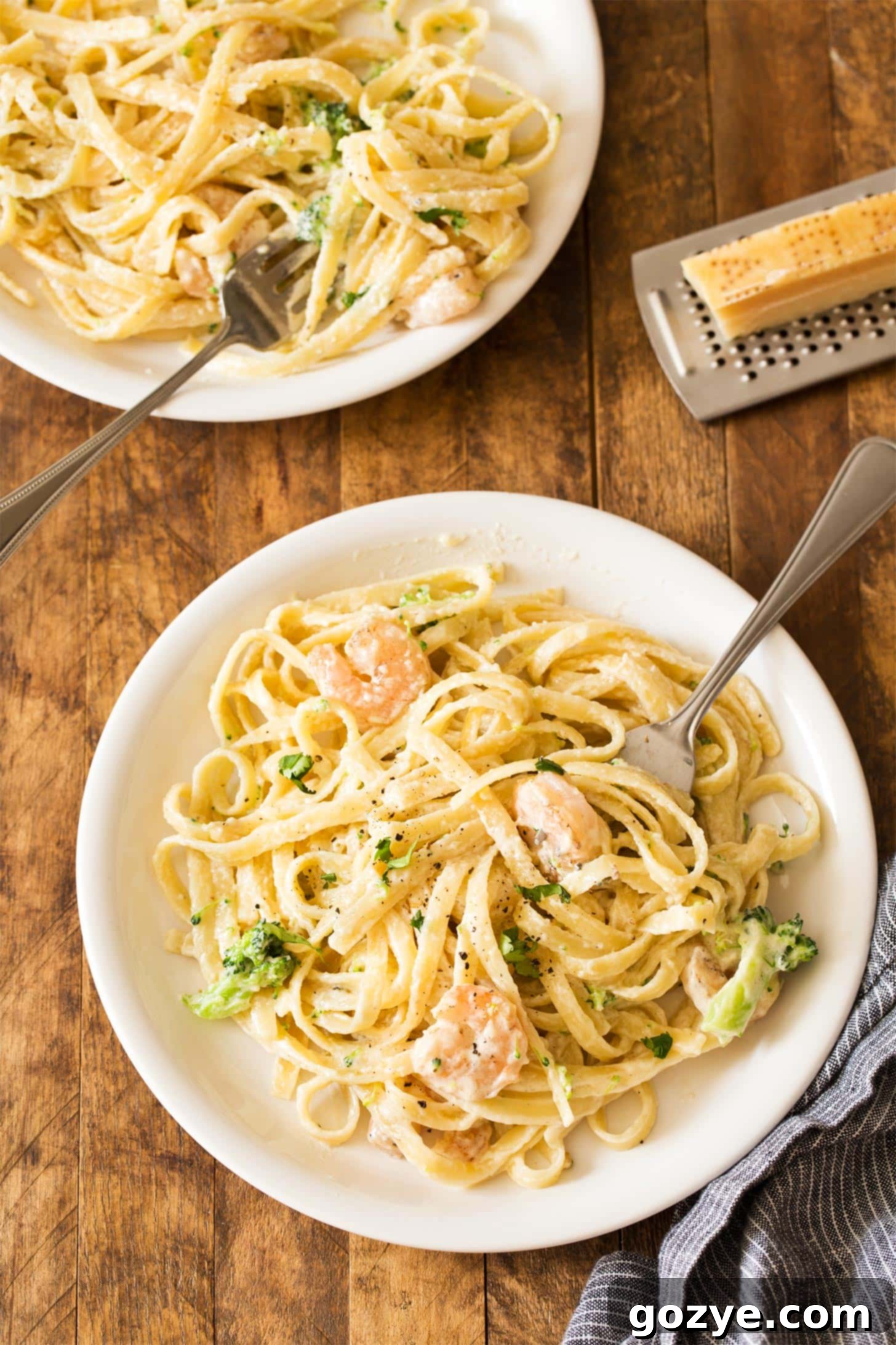 Shrimp fettuccine alfredo plated and garnished, showcasing the homemade alfredo sauce coating the pasta and shrimp.