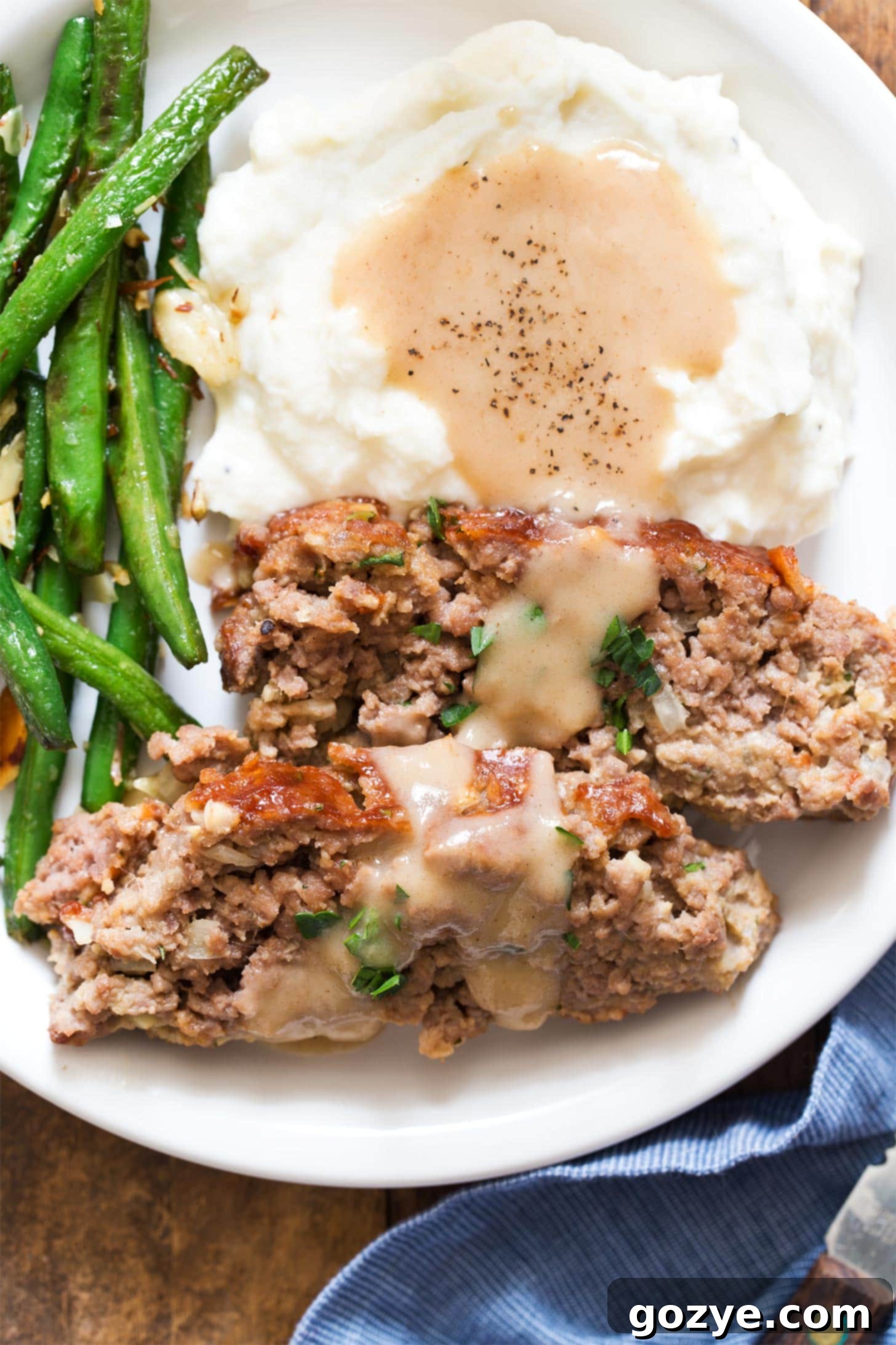 Close up of meatloaf for two with mashed potatoes, gravy, and green beans - a delicious and comforting meal.