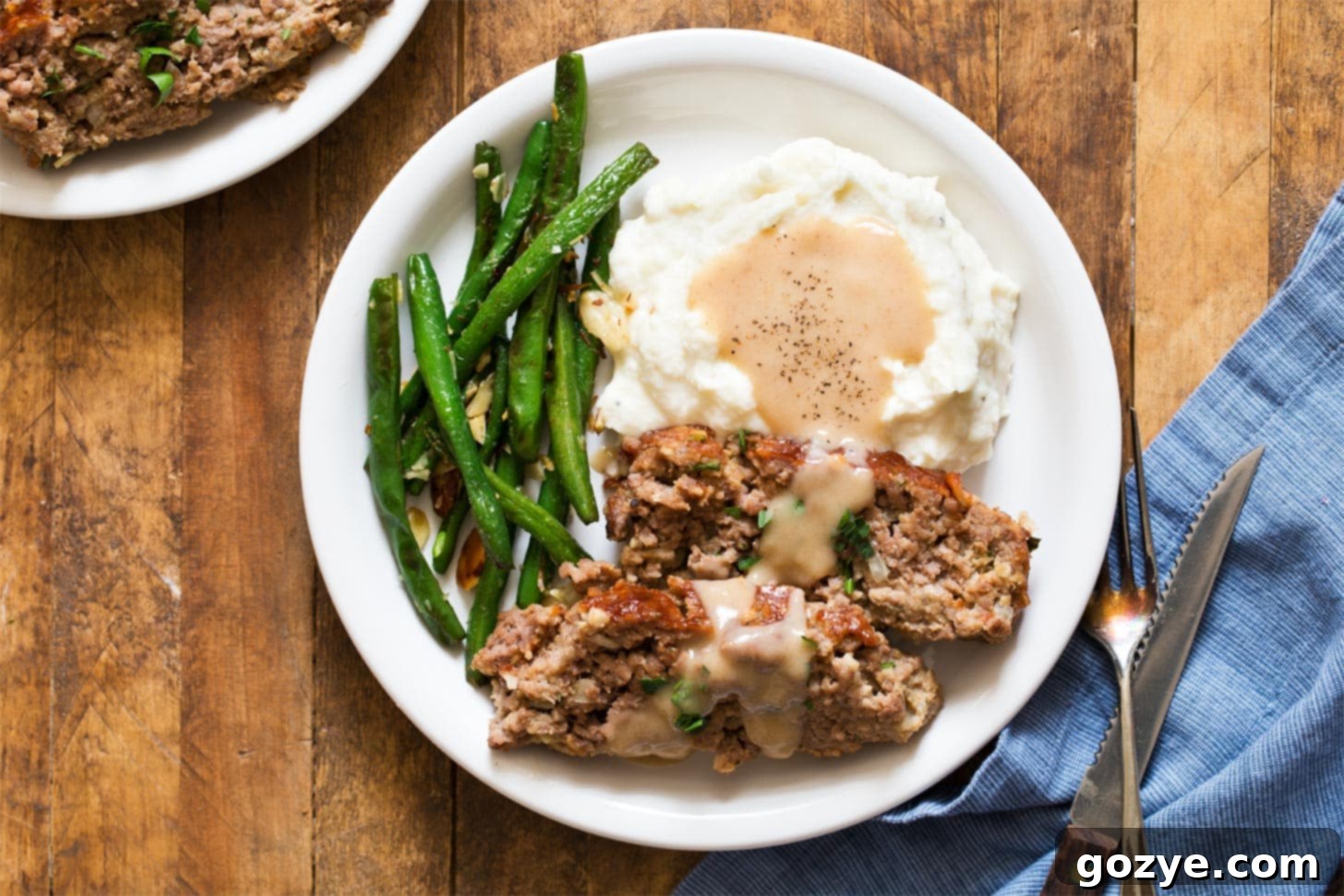 Meatloaf recipe for two with mashed potatoes, gravy, and green beans - a classic comfort food trio.